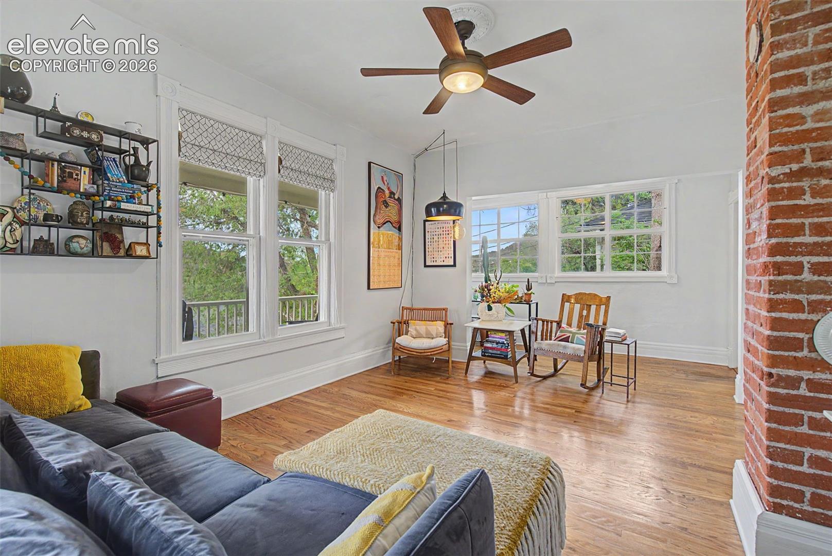 Living area featuring hardwood flooring, exposed brick, and natural lighting