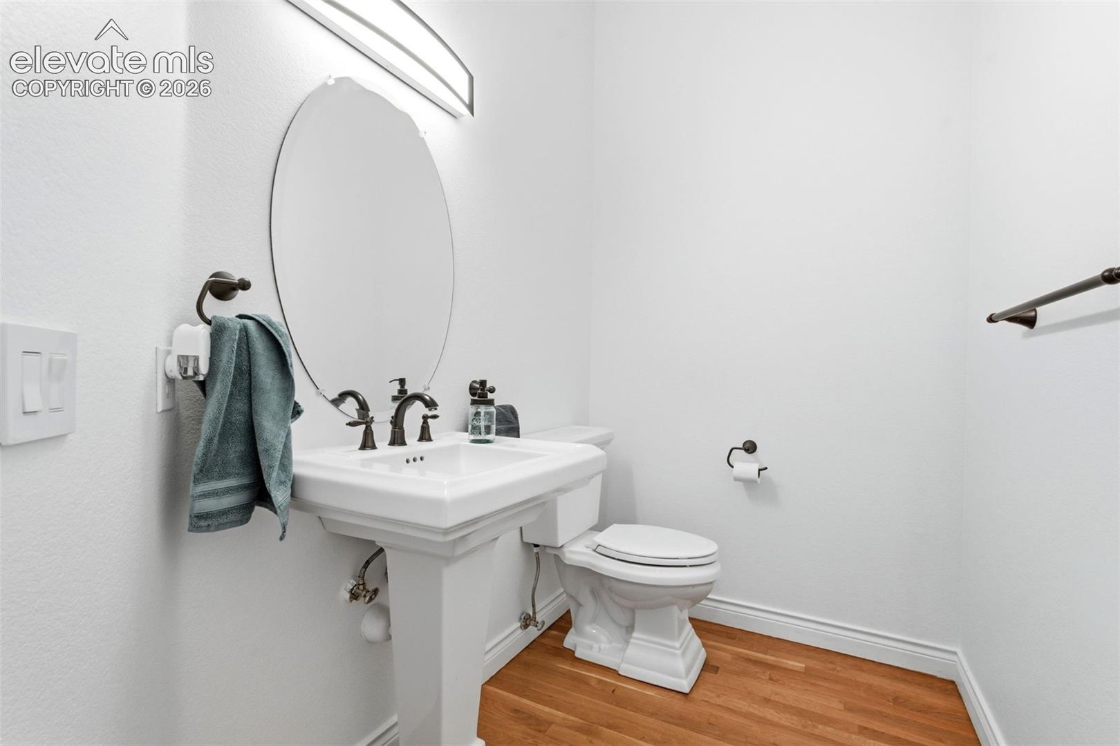 Pedestal sink with oil-rubbed bronze fixtures, oval mirror, and a wall-mounted light fixture