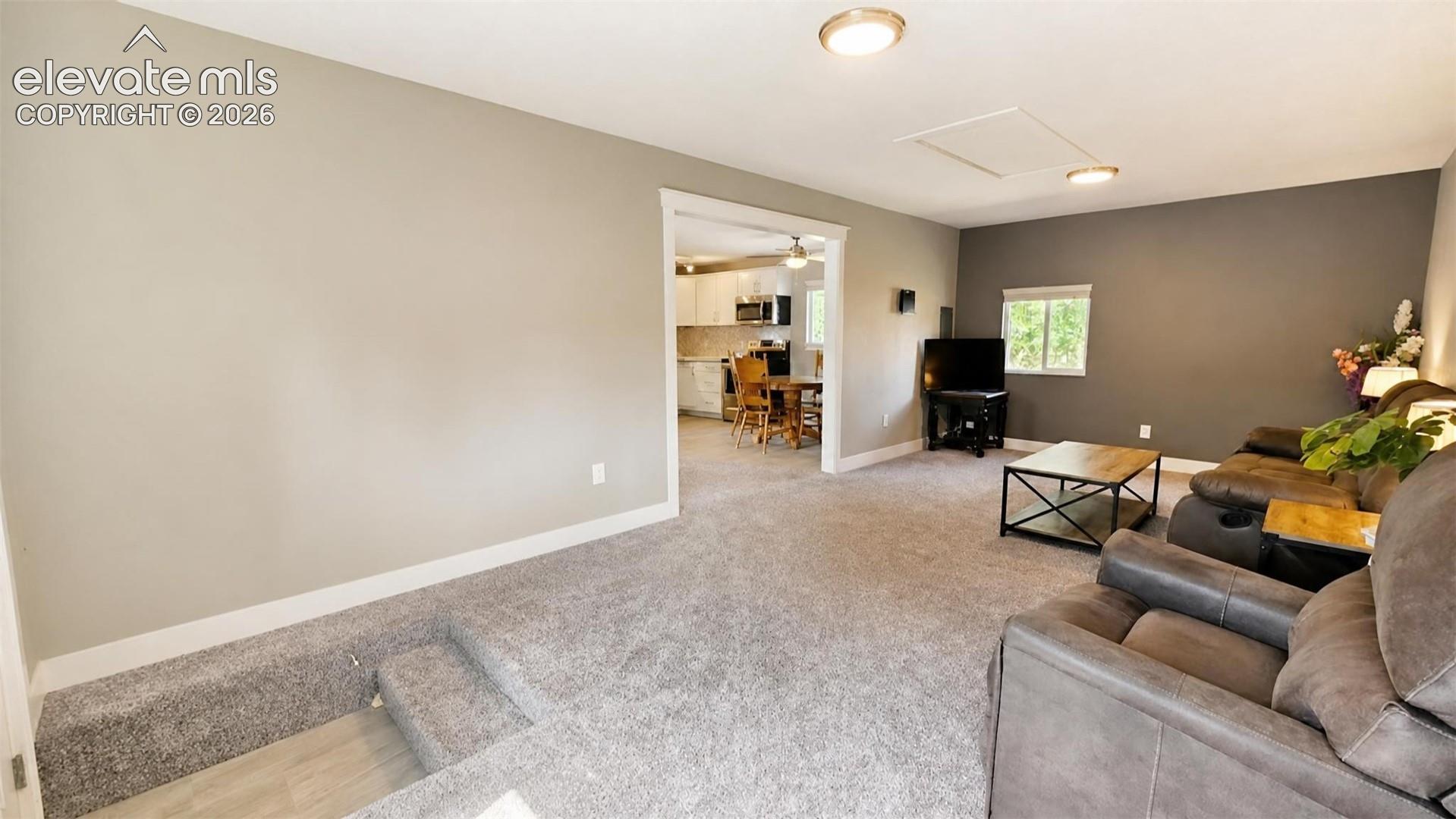 Carpeted living area with recessed lighting and a window