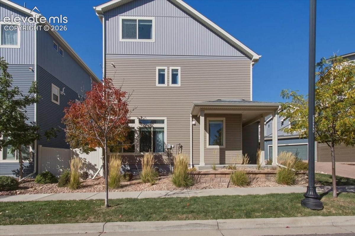 Two-story exterior with multi-toned siding, covered front entry, and a stone-faced retaining wall