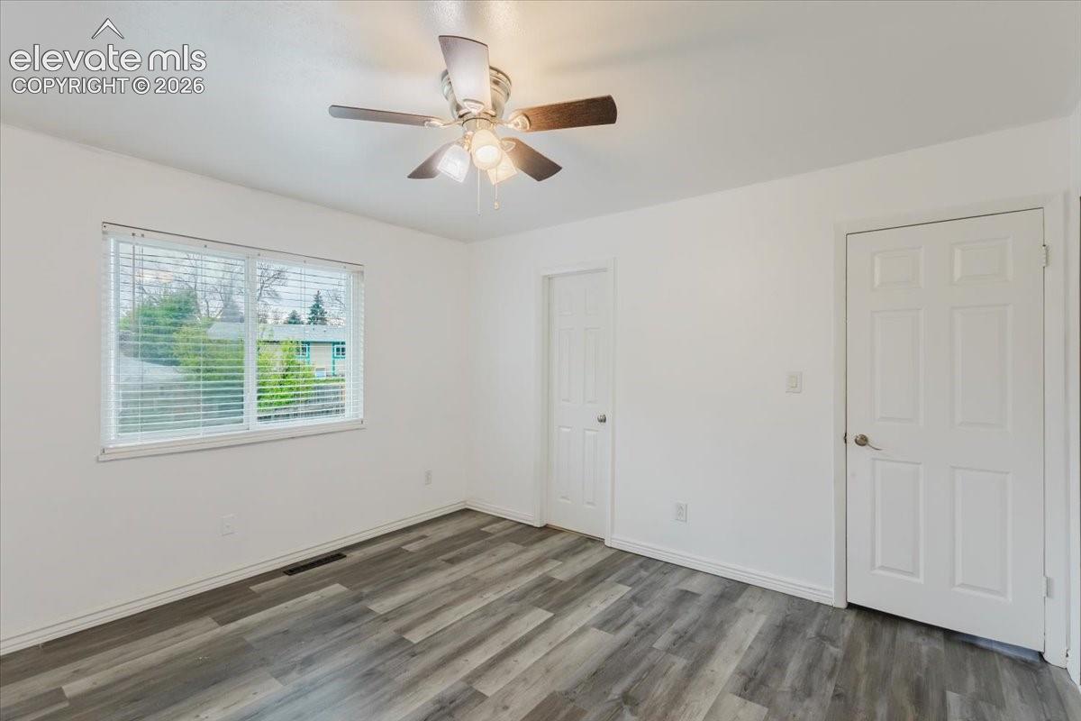 Room featuring wood-finish flooring, white baseboards, and a ceiling fan with integrated lighting