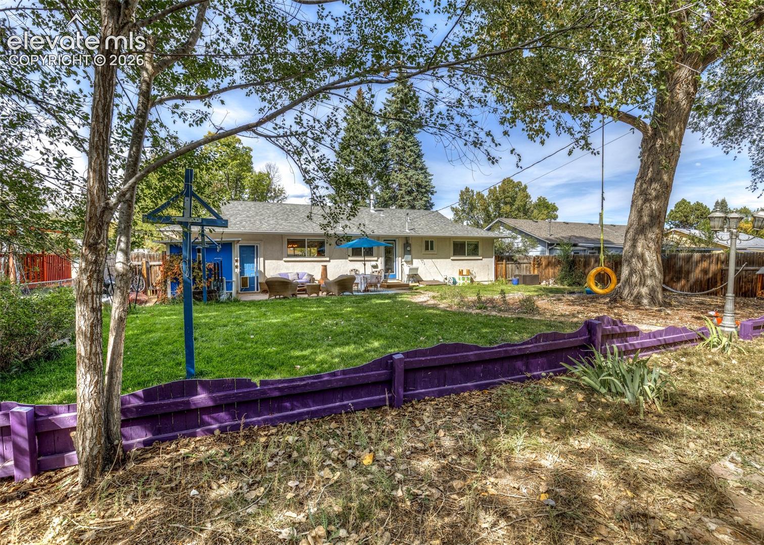 Expansive backyard featuring a lush lawn, mature trees, and an exterior patio with outdoor seating
