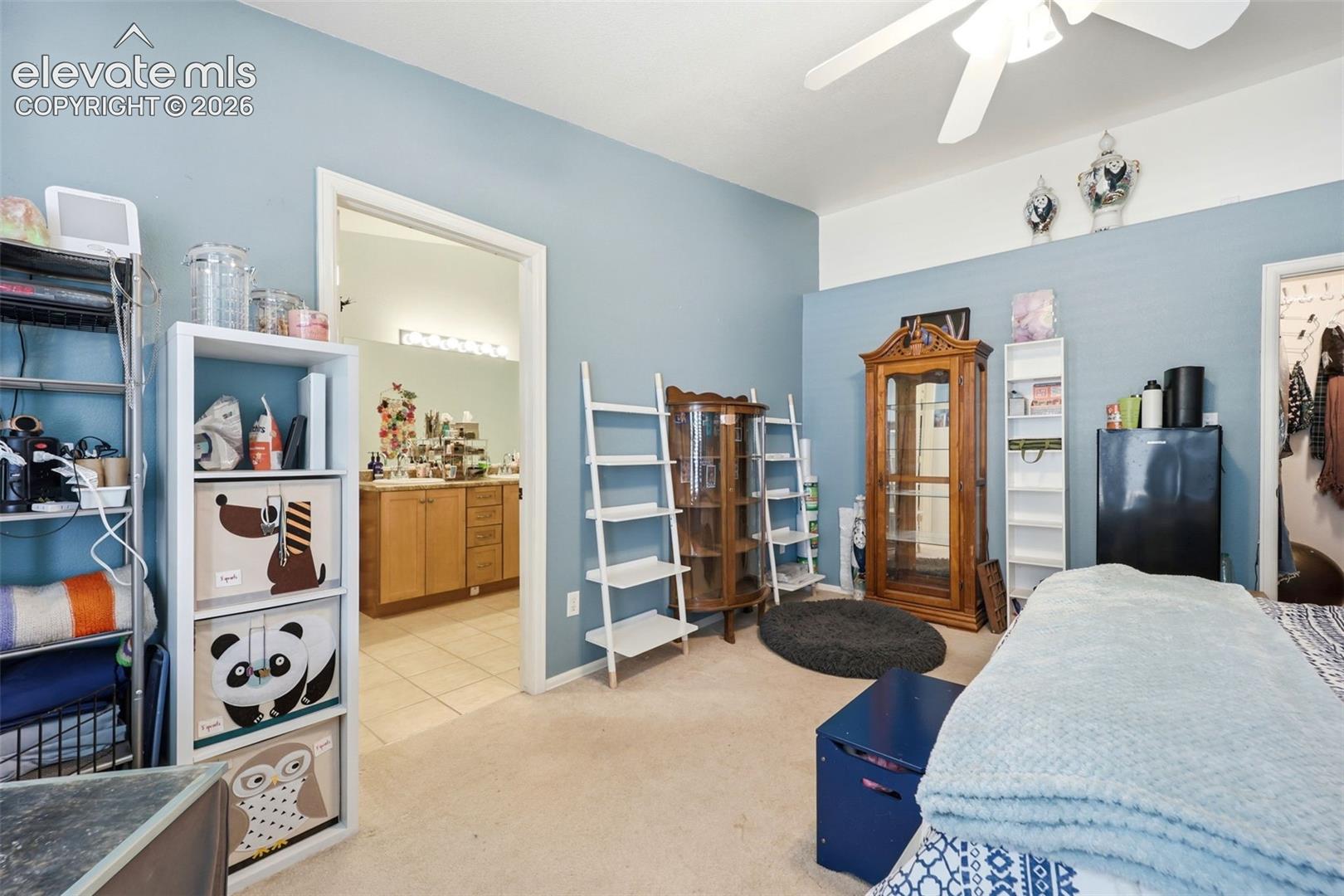 Spacious room with light blue wall paint, light neutral carpet flooring, and a ceiling fan