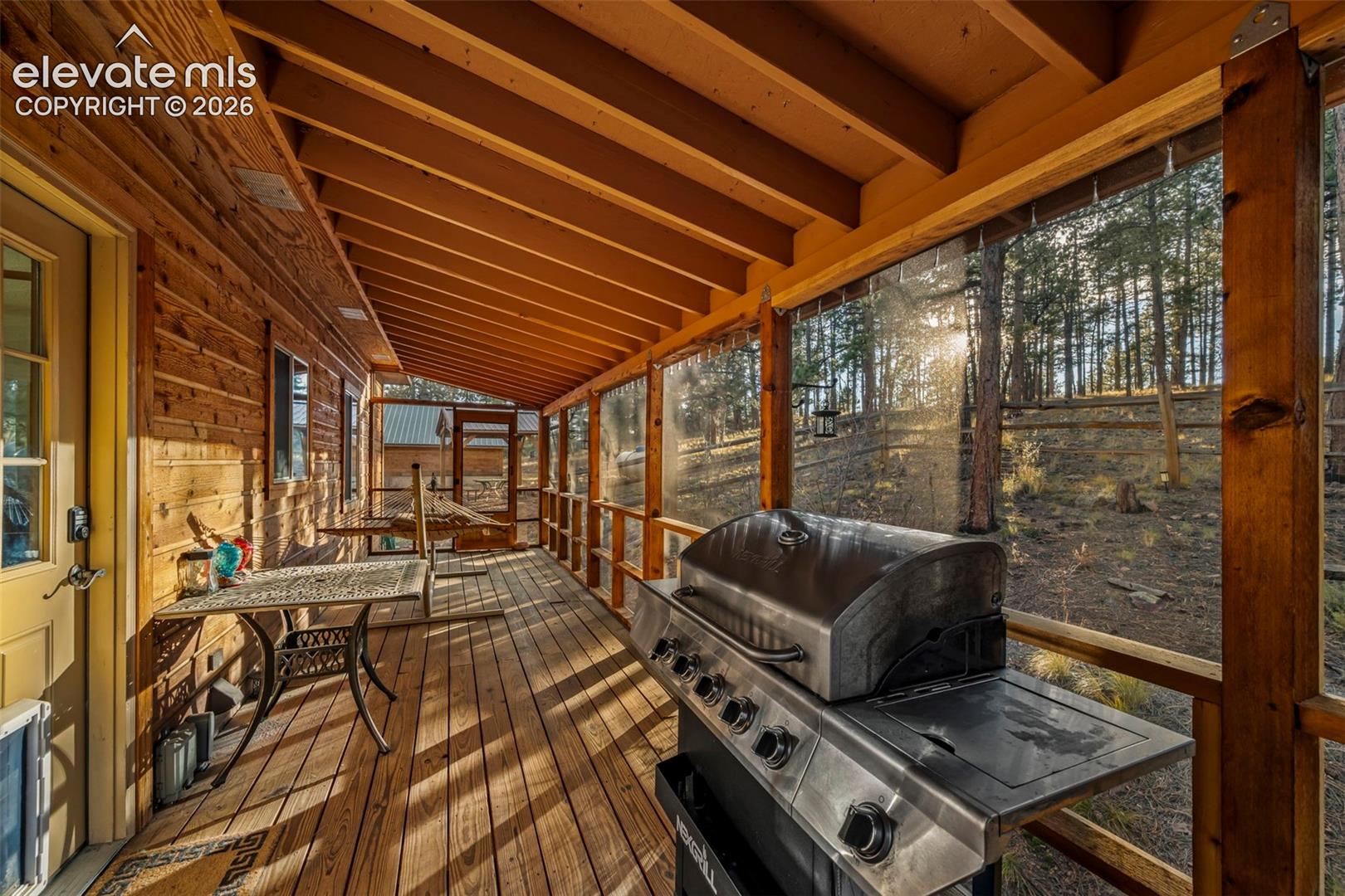 Screened-in porch featuring exposed beam ceiling, natural wood-finish siding, and wood decking