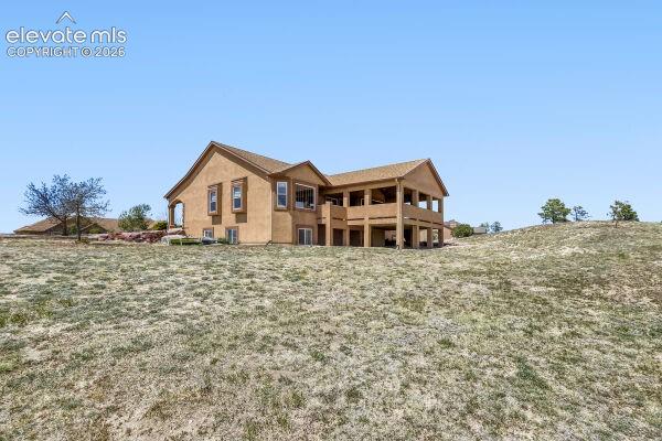 Stucco exterior with multiple windows, featuring a covered upper-level deck and a lower-level covered patio