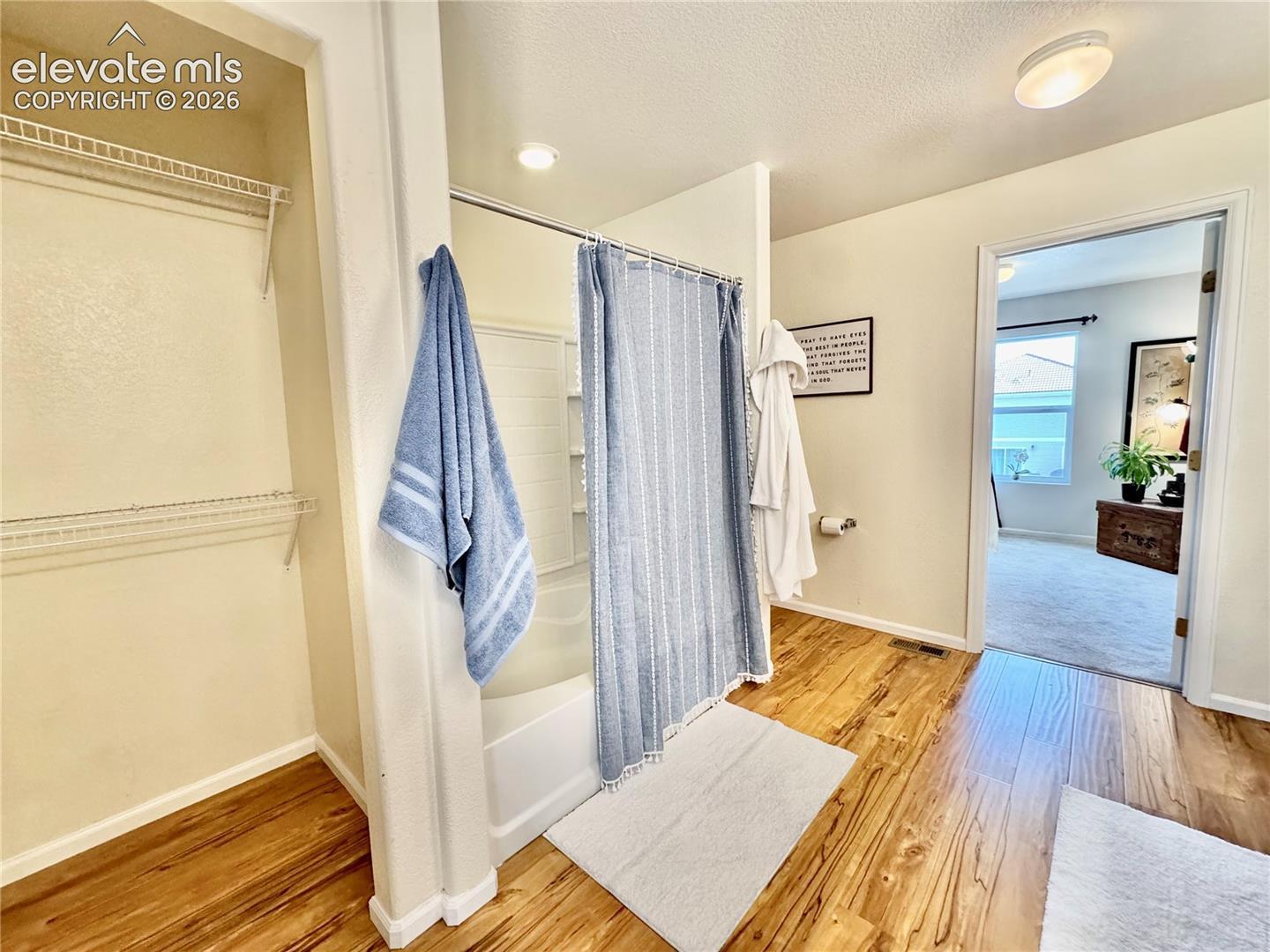 Bathroom featuring wood-finish flooring, a combination shower and tub, and overhead lighting