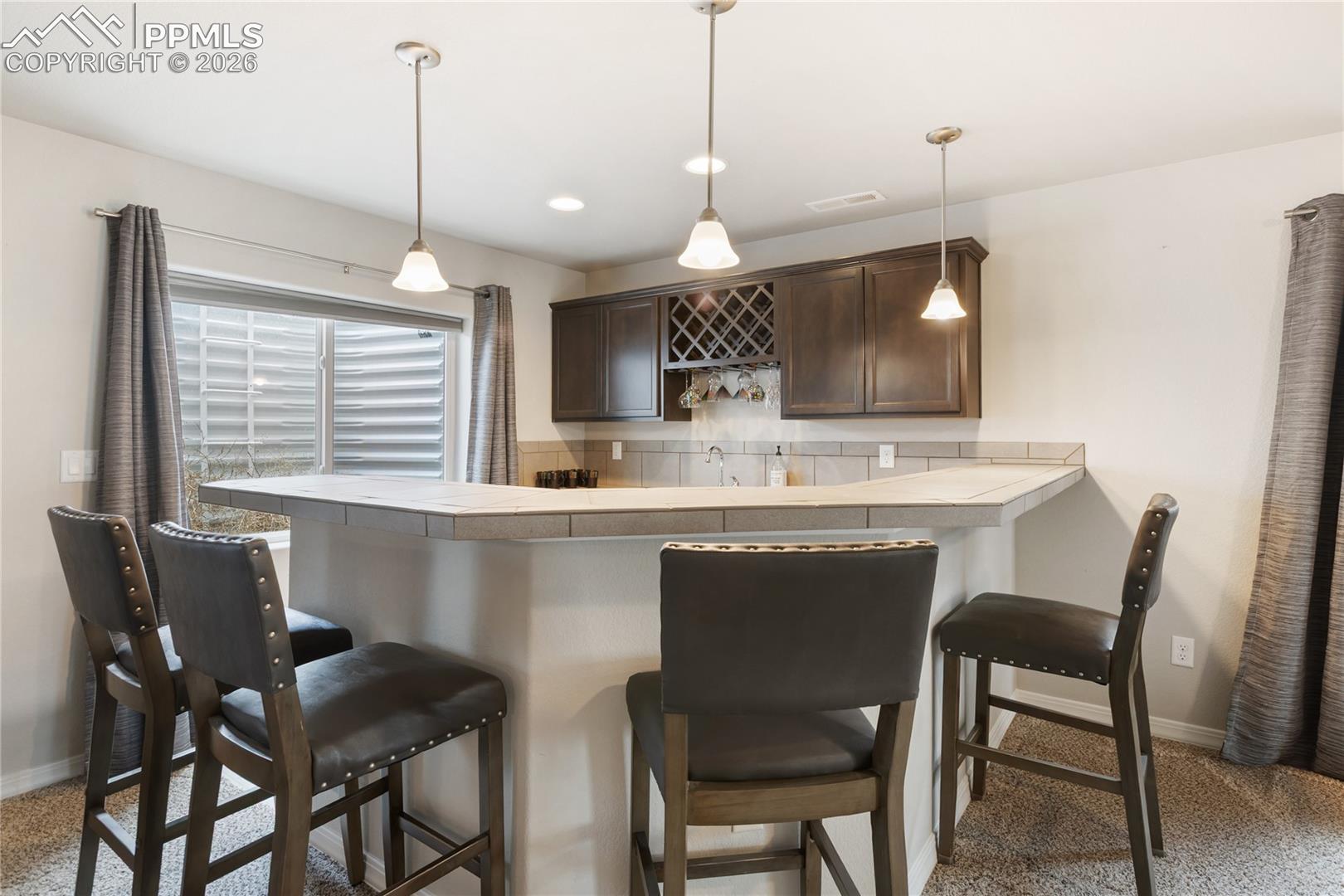 Downstairs mini bar area with seating, pendant lighting, and great space for entertaining