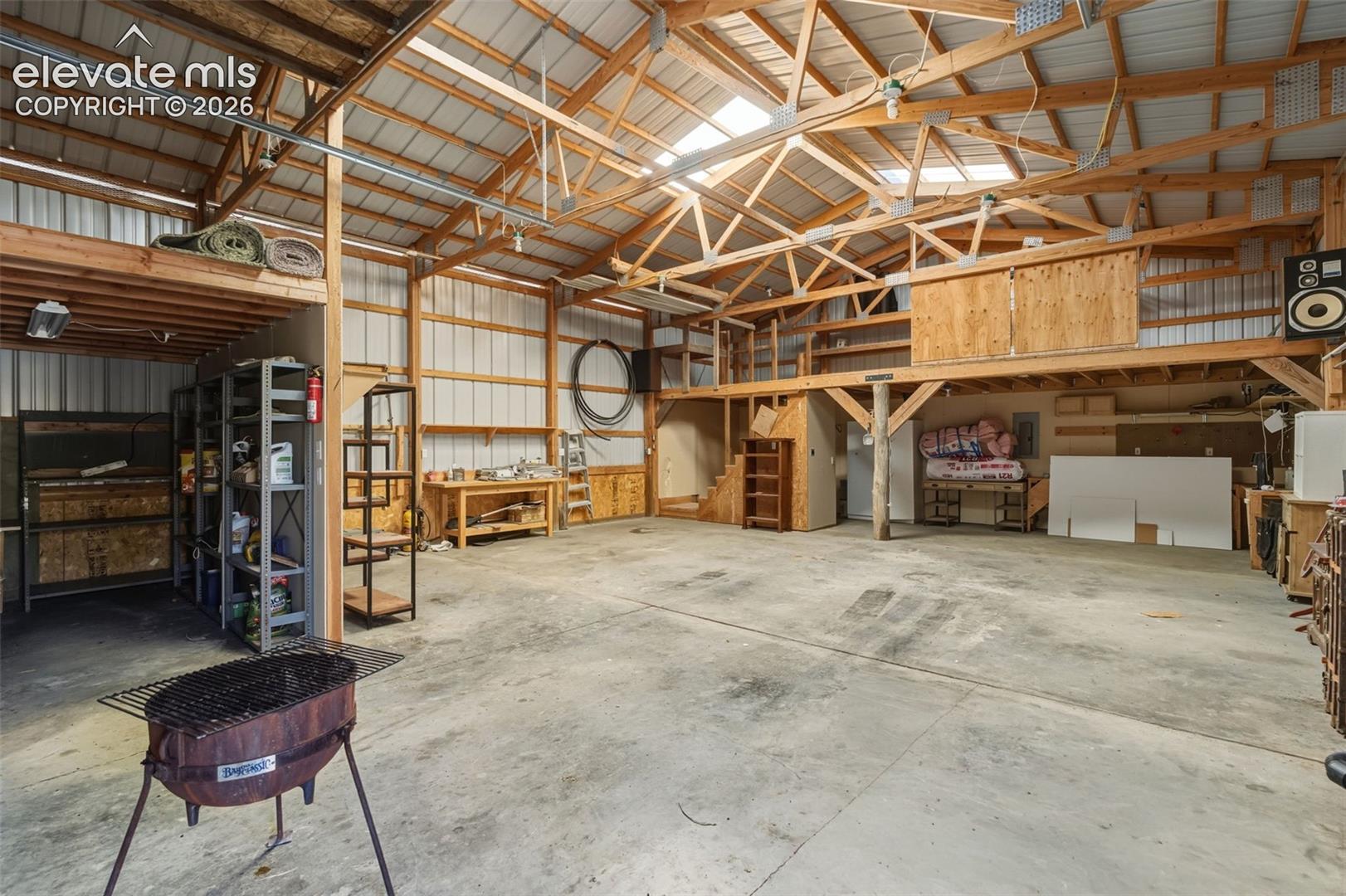 Expansive concrete flooring with a high vaulted ceiling, exposed wood beam construction, and a metal roof