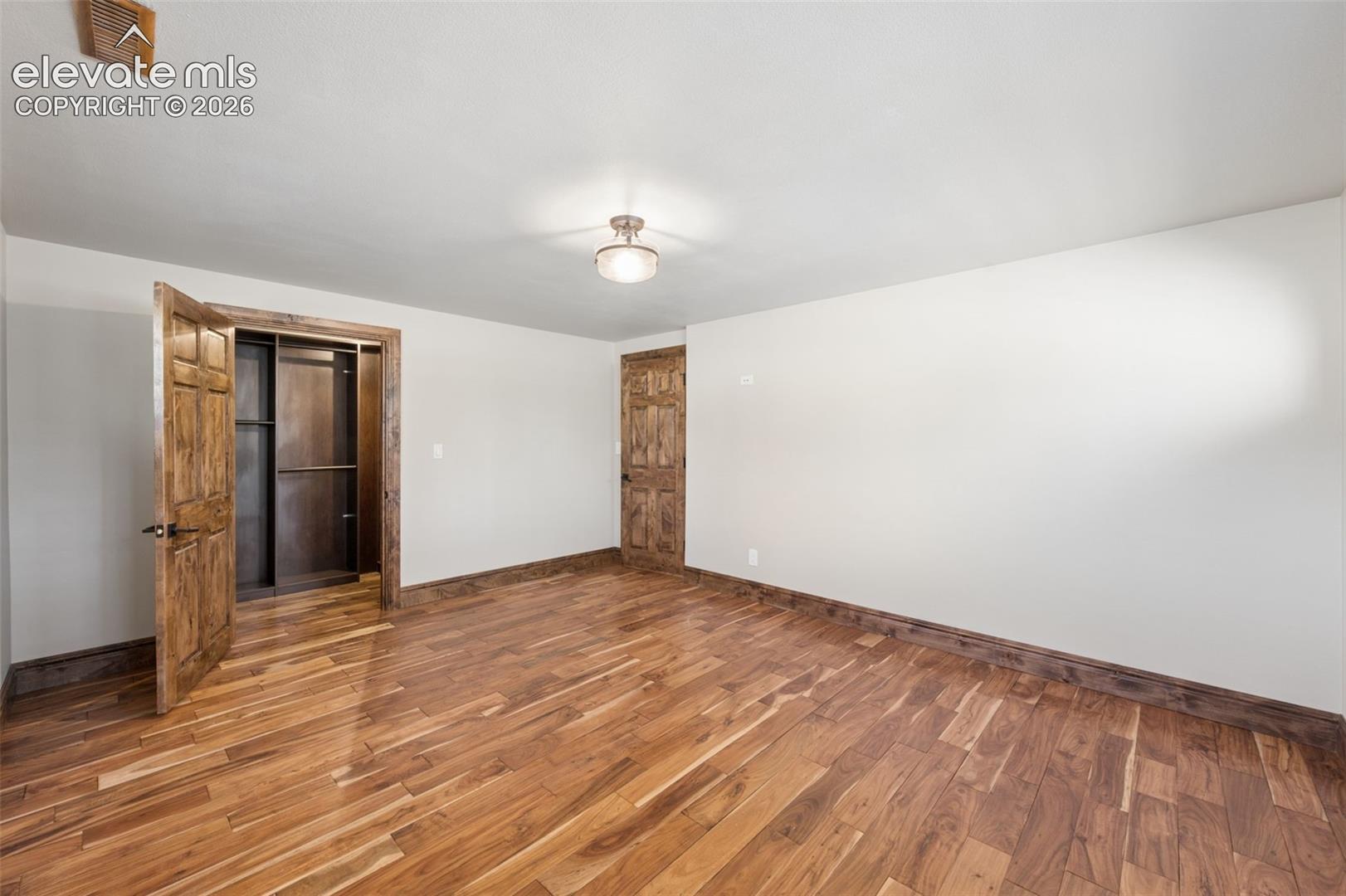 Interior room featuring wood-finish flooring, wood-paneled interior doors, and built-in closet shelving