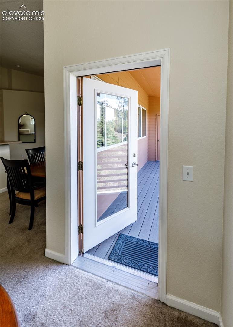Full-lite exterior door with brushed metal hardware, opening onto a gray composite deck