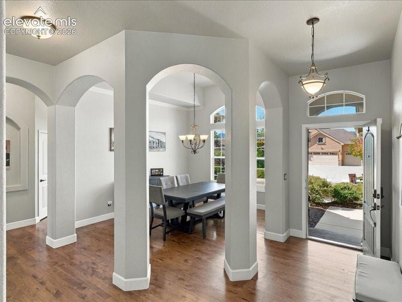 Entryway featuring wood-finish flooring, an arched transom window, and a decorative pendant light