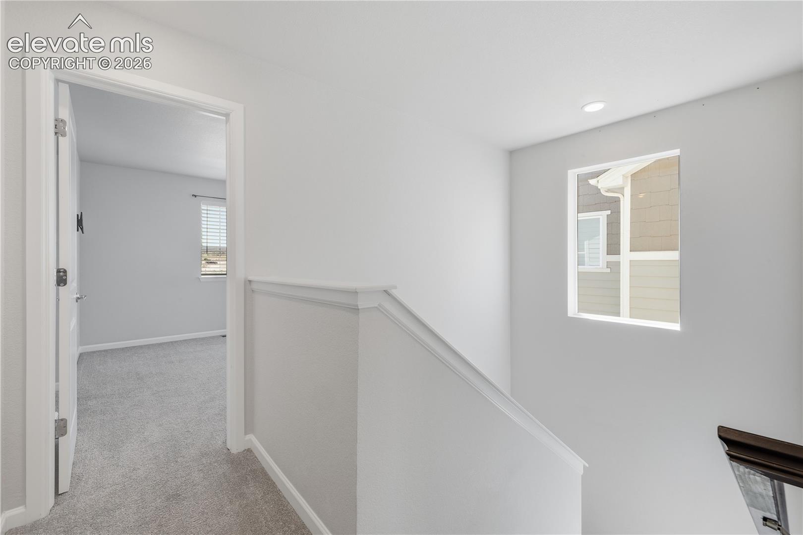 Upper-level hallway with light gray walls, white trim, and a window providing exterior light