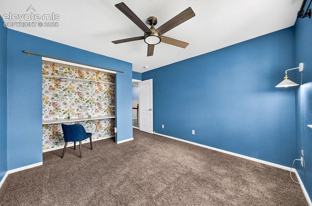 Built-in shelving with floral wallpaper, contemporary ceiling fan, and wall-mounted light fixture