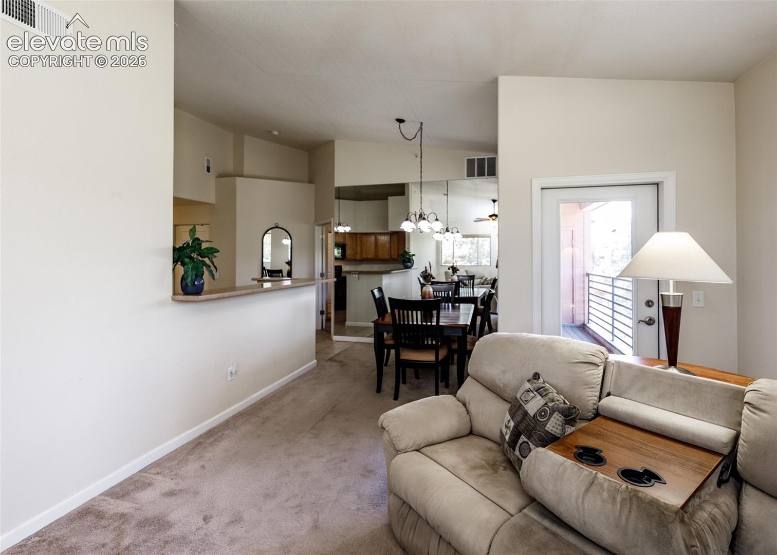 Vaulted ceilings with recessed lighting, breakfast bar, mirror wall accents, and glass-paneled exterior door
