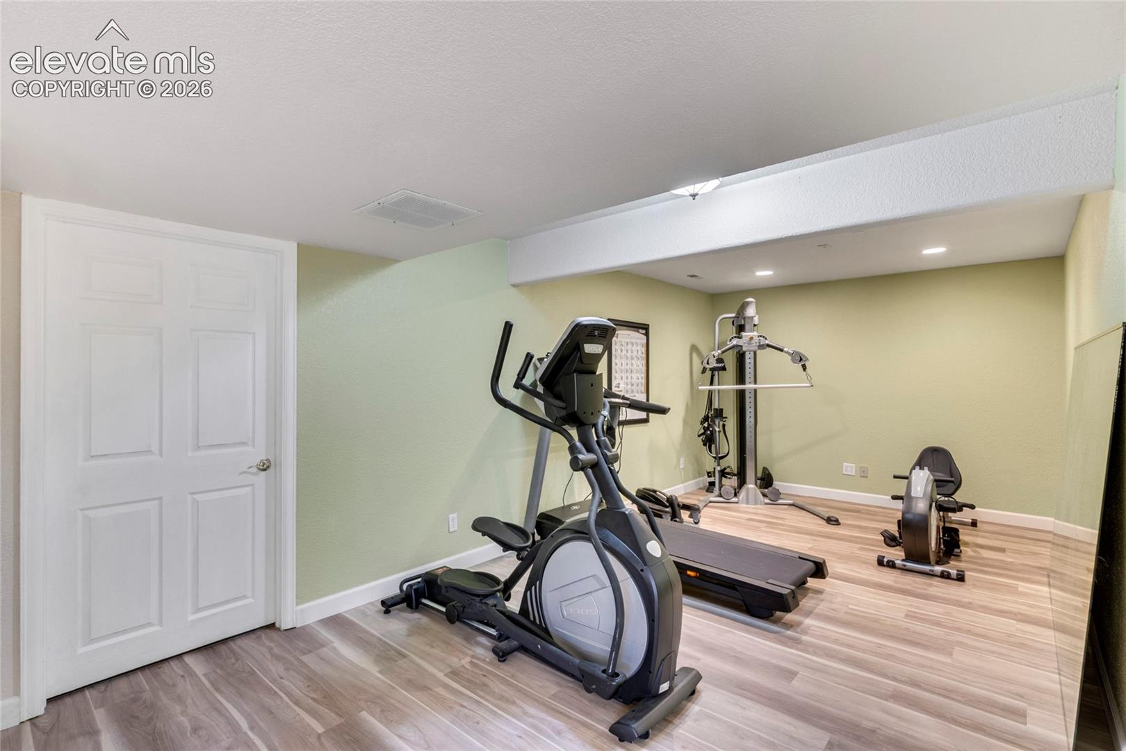 Finished room with wood-finish flooring, recessed lighting, and a six-panel interior door