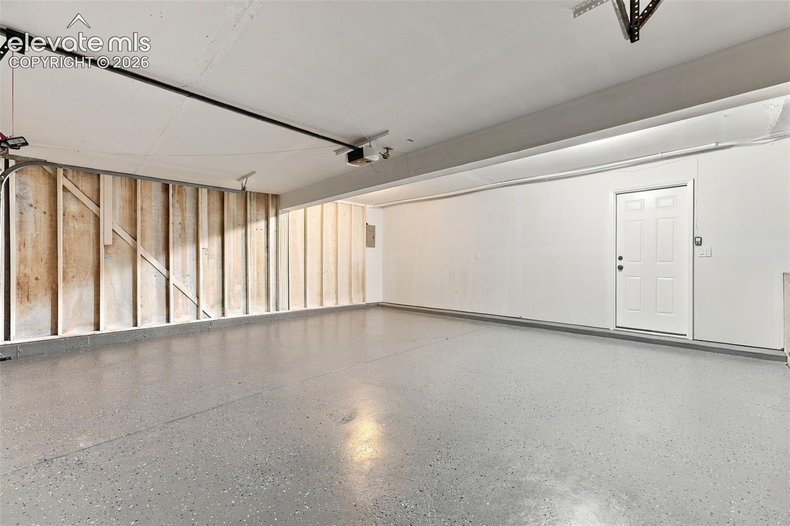 Two-car garage featuring epoxy-coated flooring, white drywall, and a dedicated pedestrian entry door