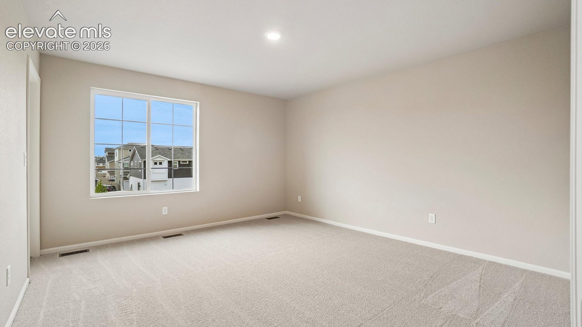 Light-colored walls, recessed ceiling lighting, light-toned carpet flooring, and a large window with grid panes
*photos of a model home*