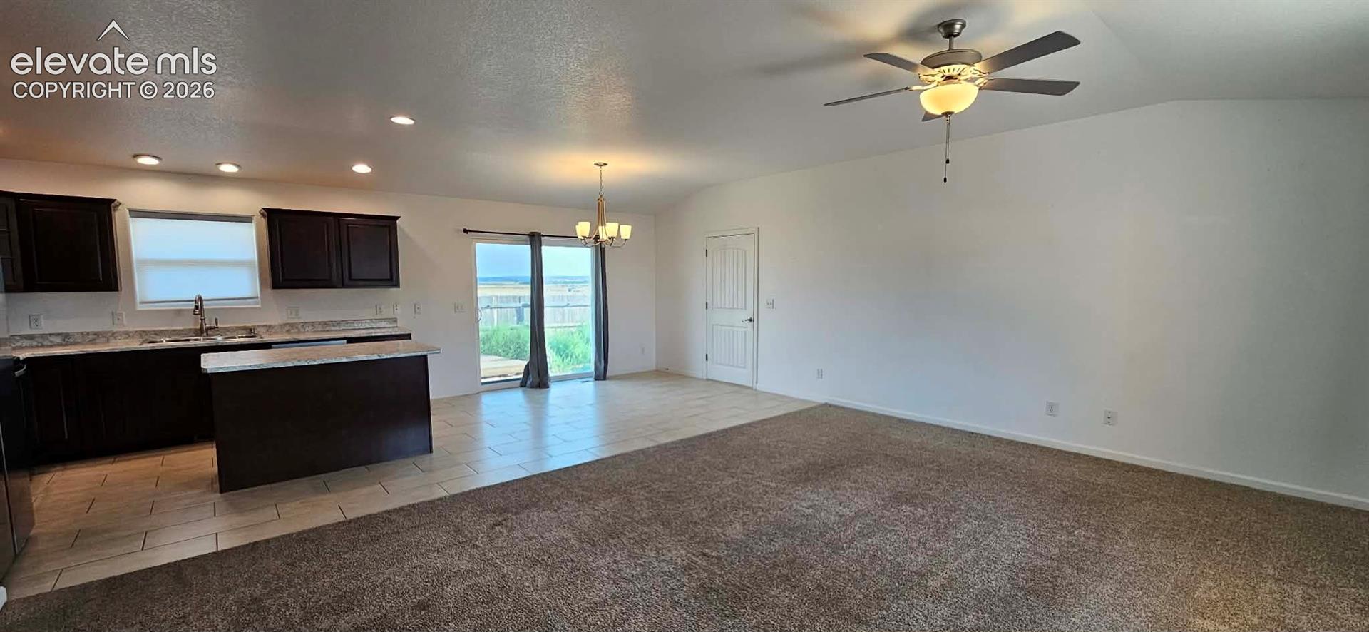 Open-concept area featuring dark-finish cabinetry, stone-patterned countertops, recessed lighting, a ceiling fan, and sliding glass doors