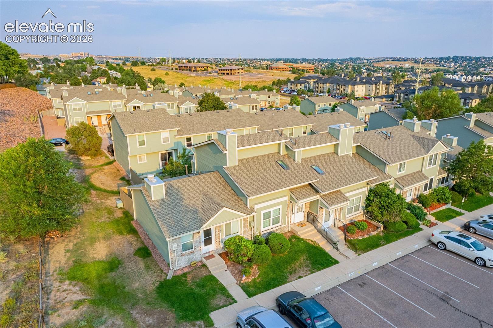 Townhome community featuring pitched roofs, multiple chimneys, and a dedicated parking area