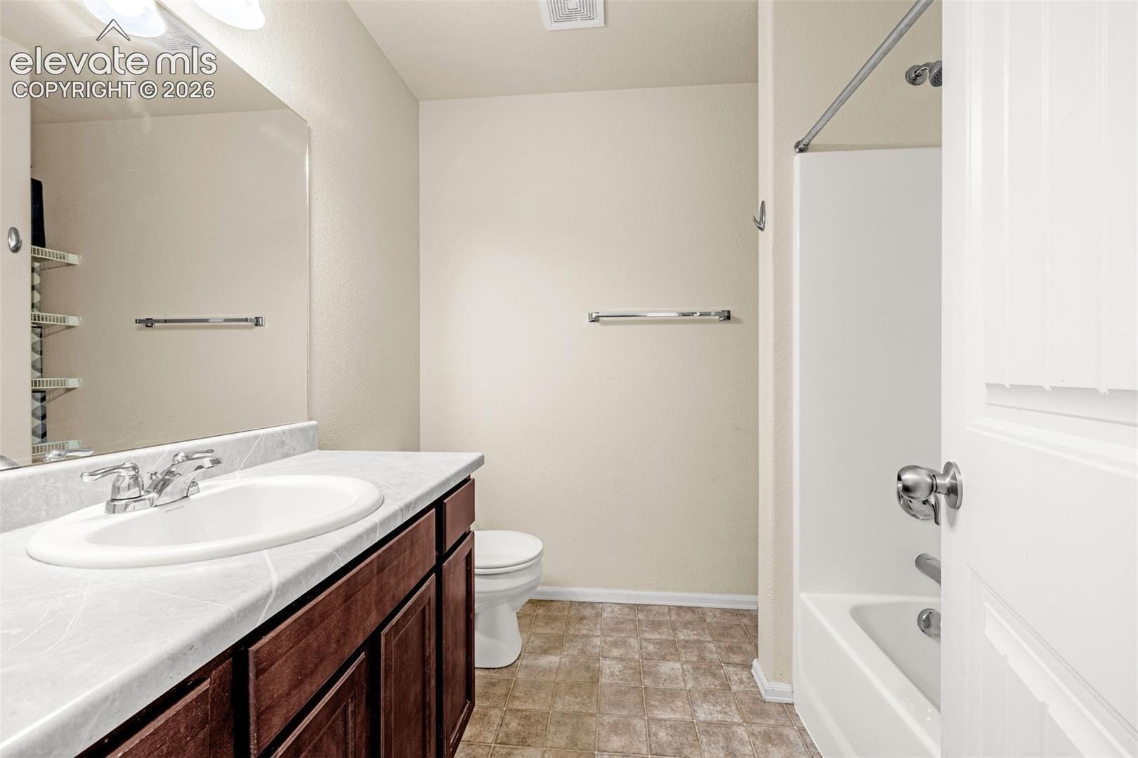 Warm-toned wood-finish vanity with an integrated sink and chrome faucet, set against light neutral walls
