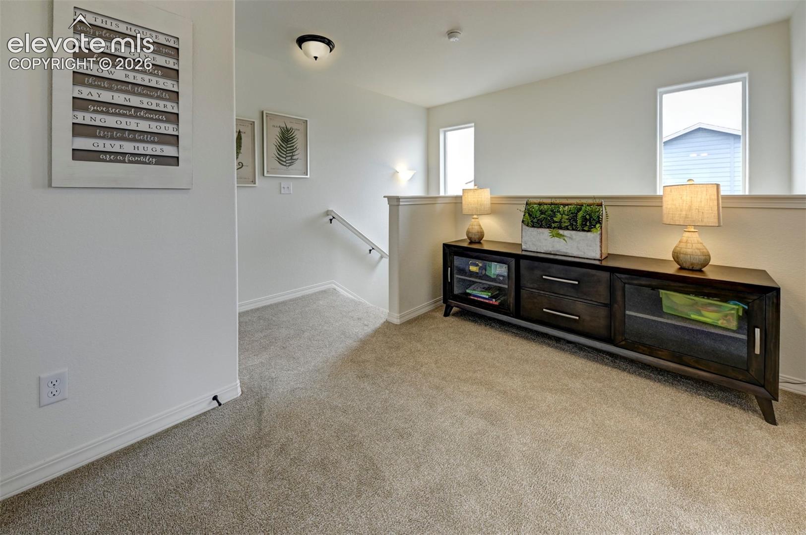 Neutral carpeted flooring, two double-hung windows, and a semi-flush mount light fixture