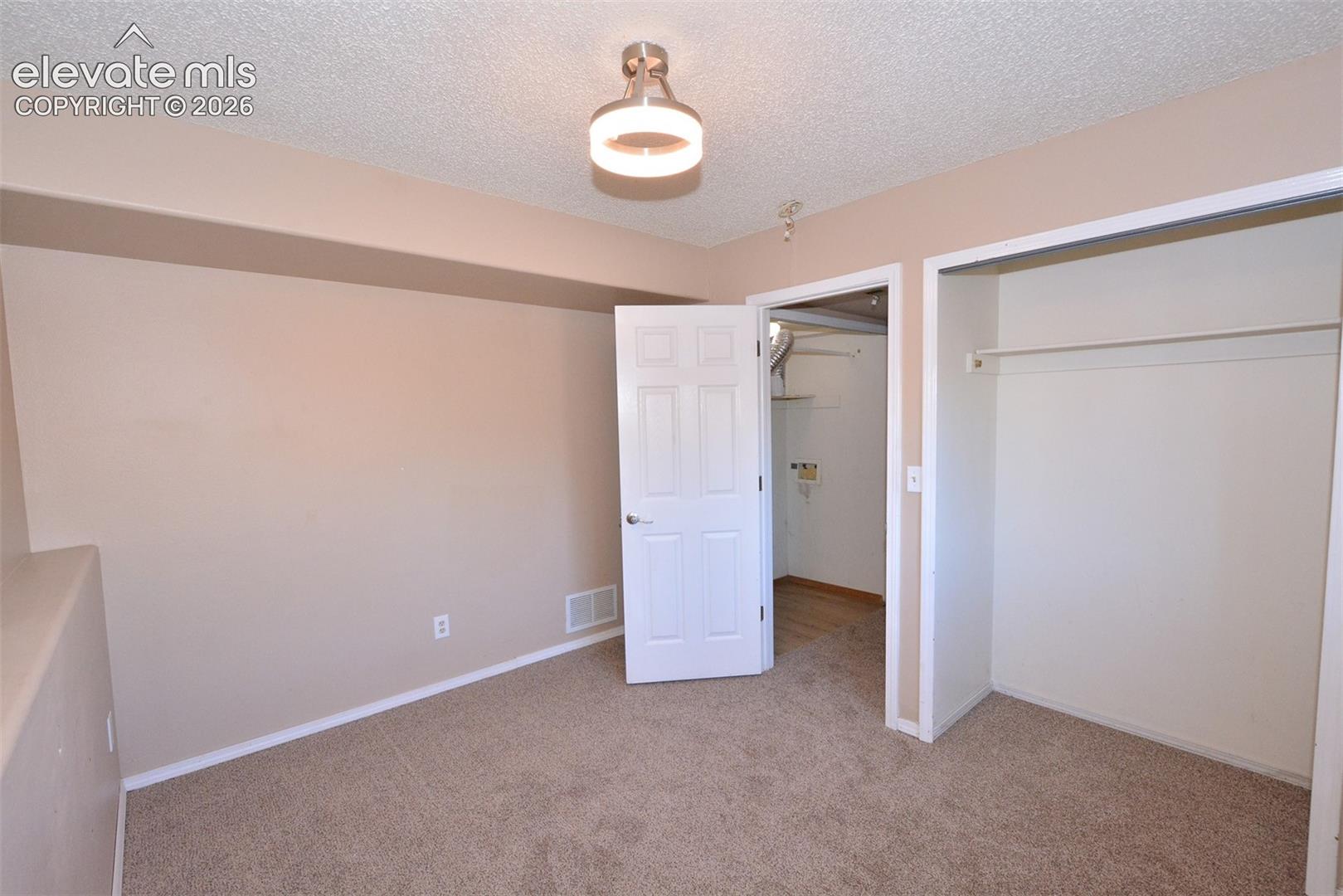 Carpeted flooring, neutral wall tones, semi-flush mount ceiling light, white trim, and a built-in closet with hanging rod