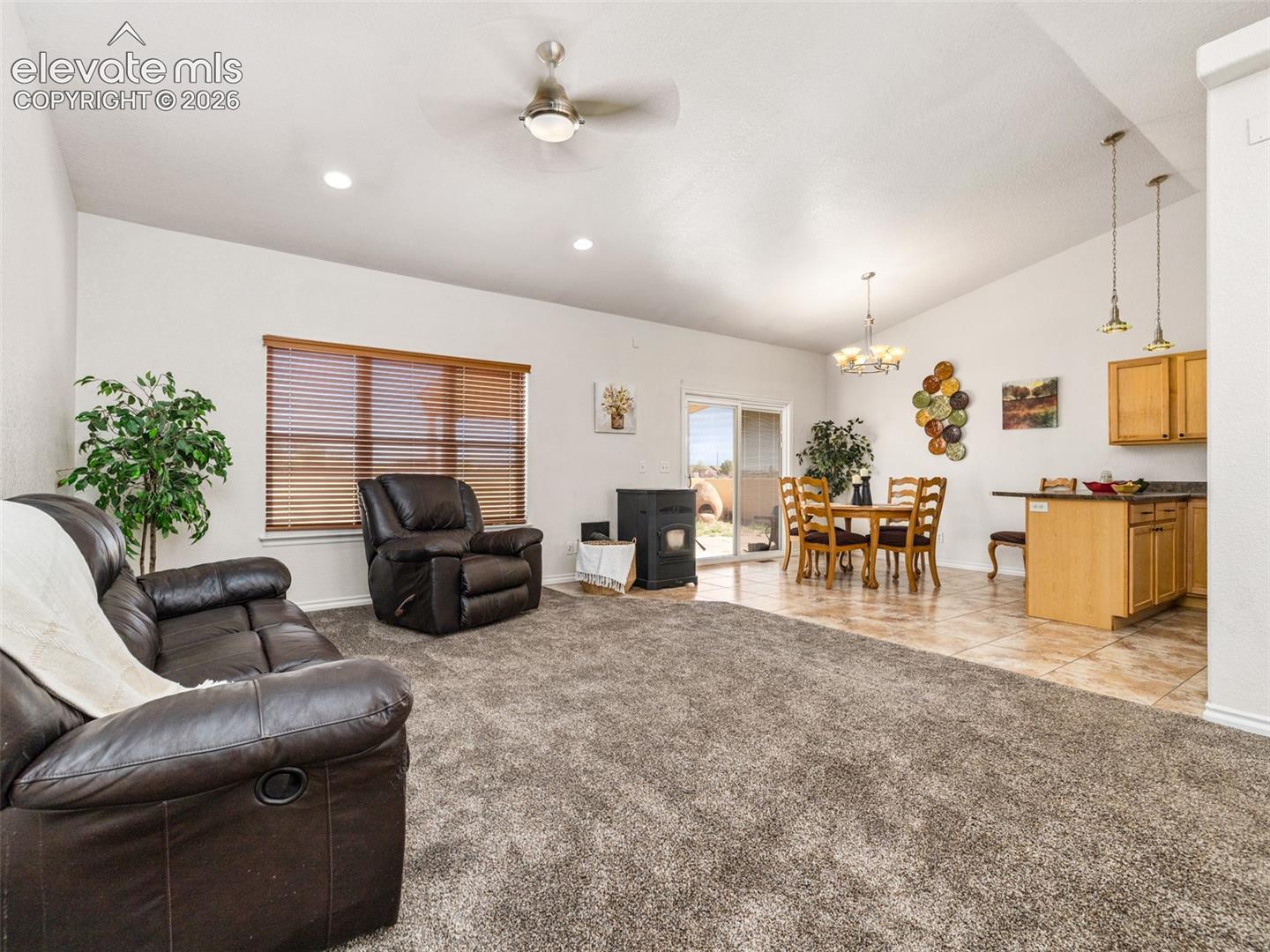 Open-concept living space featuring vaulted ceilings, recessed lighting, a sliding glass door, and a tiled dining area