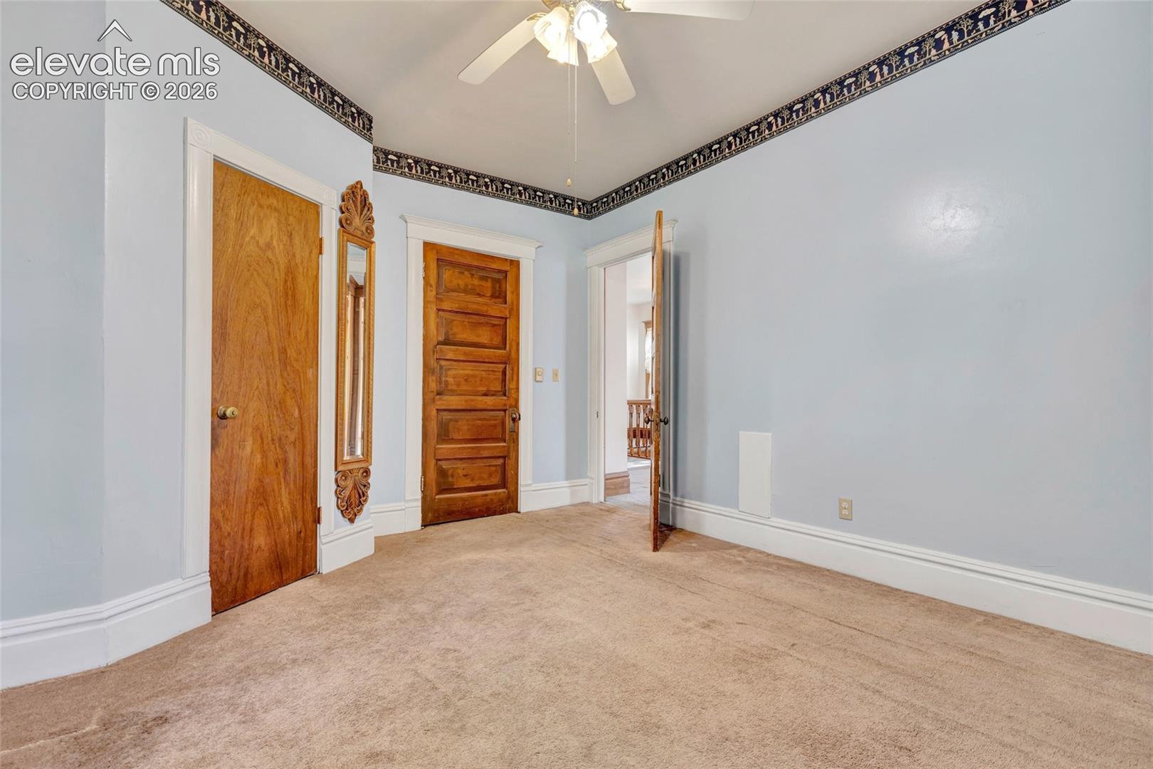 Interior space featuring five-panel solid wood doors, crown molding with decorative trim, and a ceiling-mounted light fixture