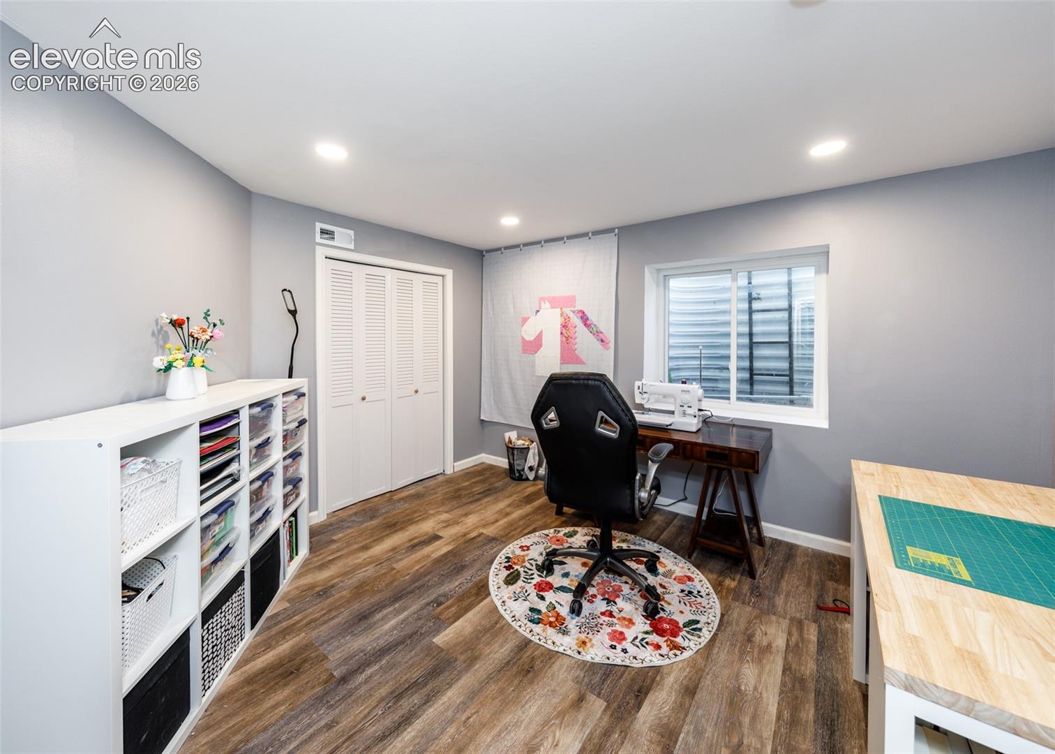 Recessed lighting, wood-finish flooring, white louvered bifold doors, and a white-framed window