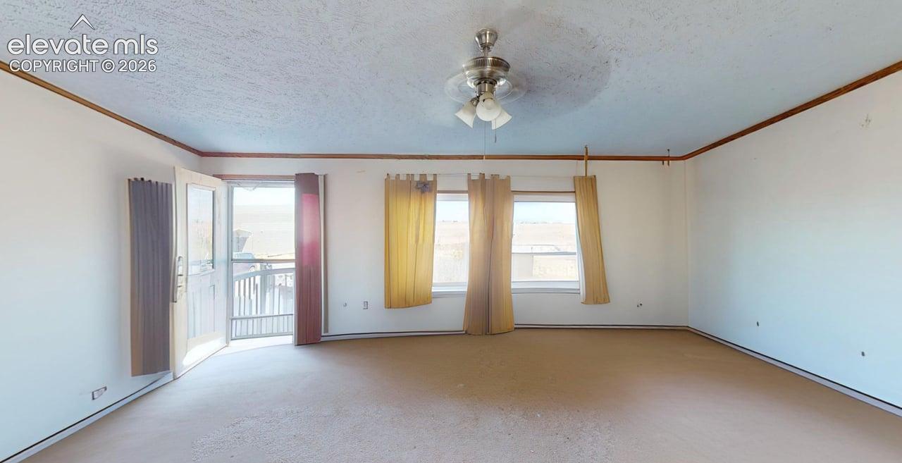 Unfurnished room with a ceiling fan, a textured ceiling, healthy amount of natural light, and crown molding