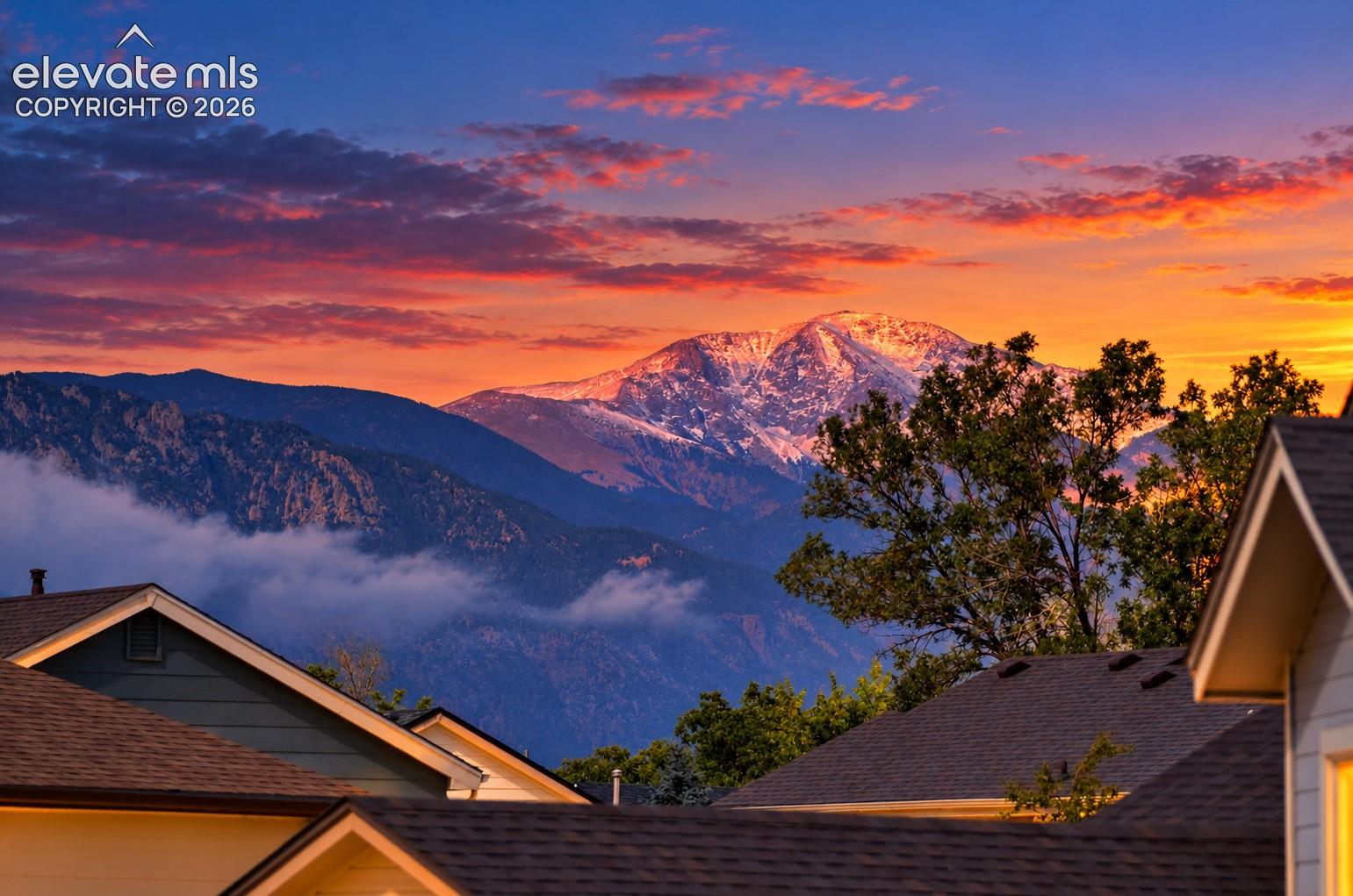 Mountain range backdrop, snow-capped peaks, and multiple property rooflines with dark shingles