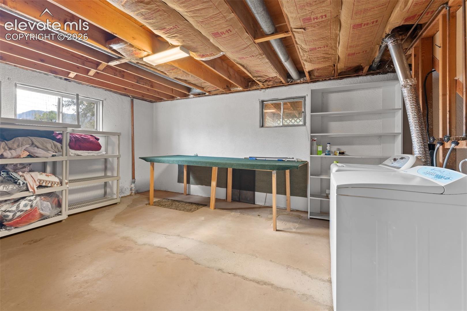 Basement utility area with exposed ceiling joists, concrete flooring, and multiple windows