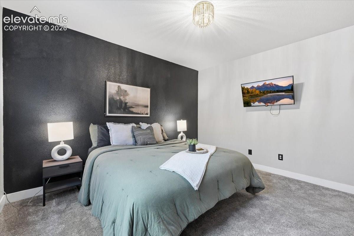 Plush carpeted flooring, a textured accent wall, and a ceiling-mounted light fixture