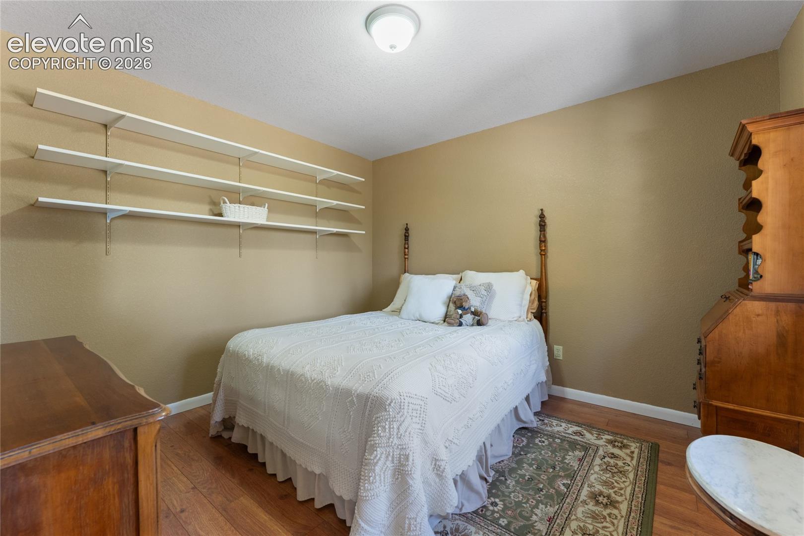 Bedroom with wood-finish flooring, neutral wall paint, and white baseboards