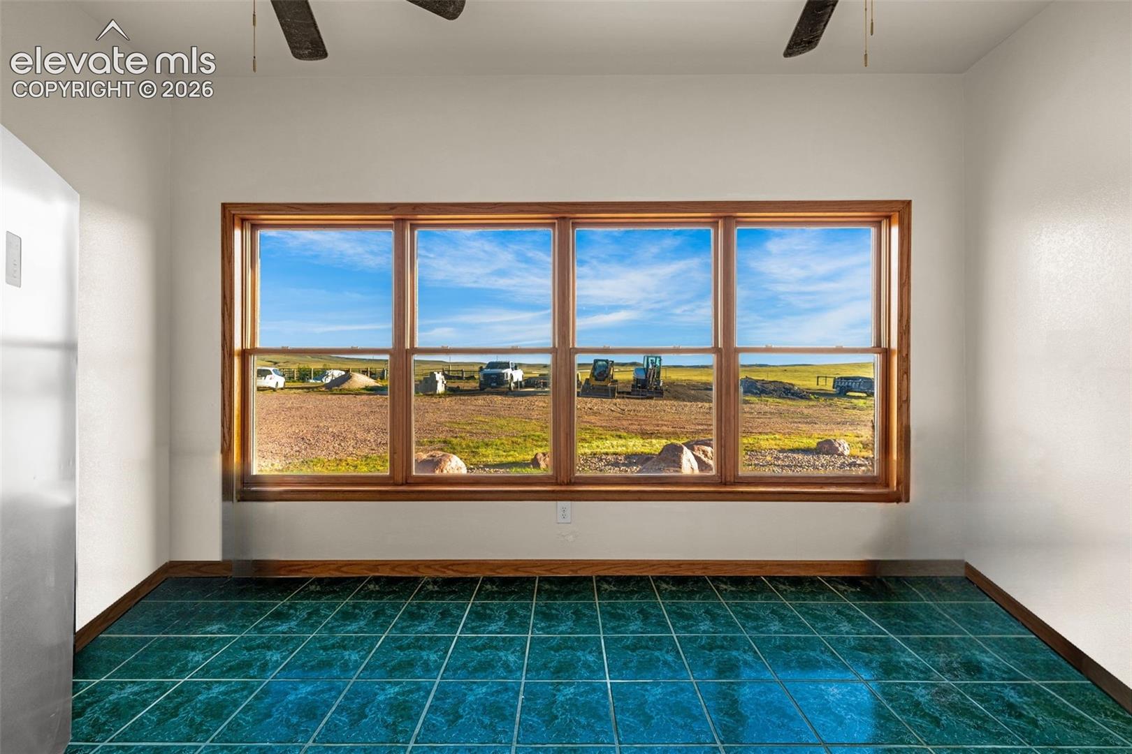Large window with wood trim, ceramic tile flooring, and ceiling fans