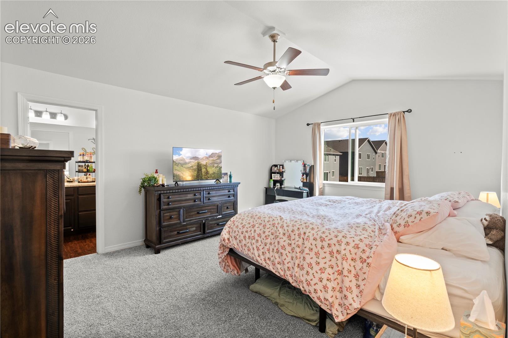 Vaulted ceilings, neutral carpeting, and a ceiling fan with integrated lighting