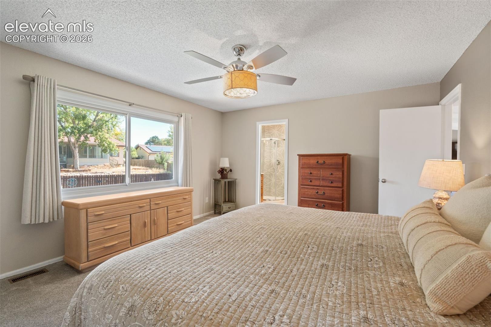 Neutral interior walls, large horizontal sliding window, and ceiling-mounted light fixture with a five-blade fan