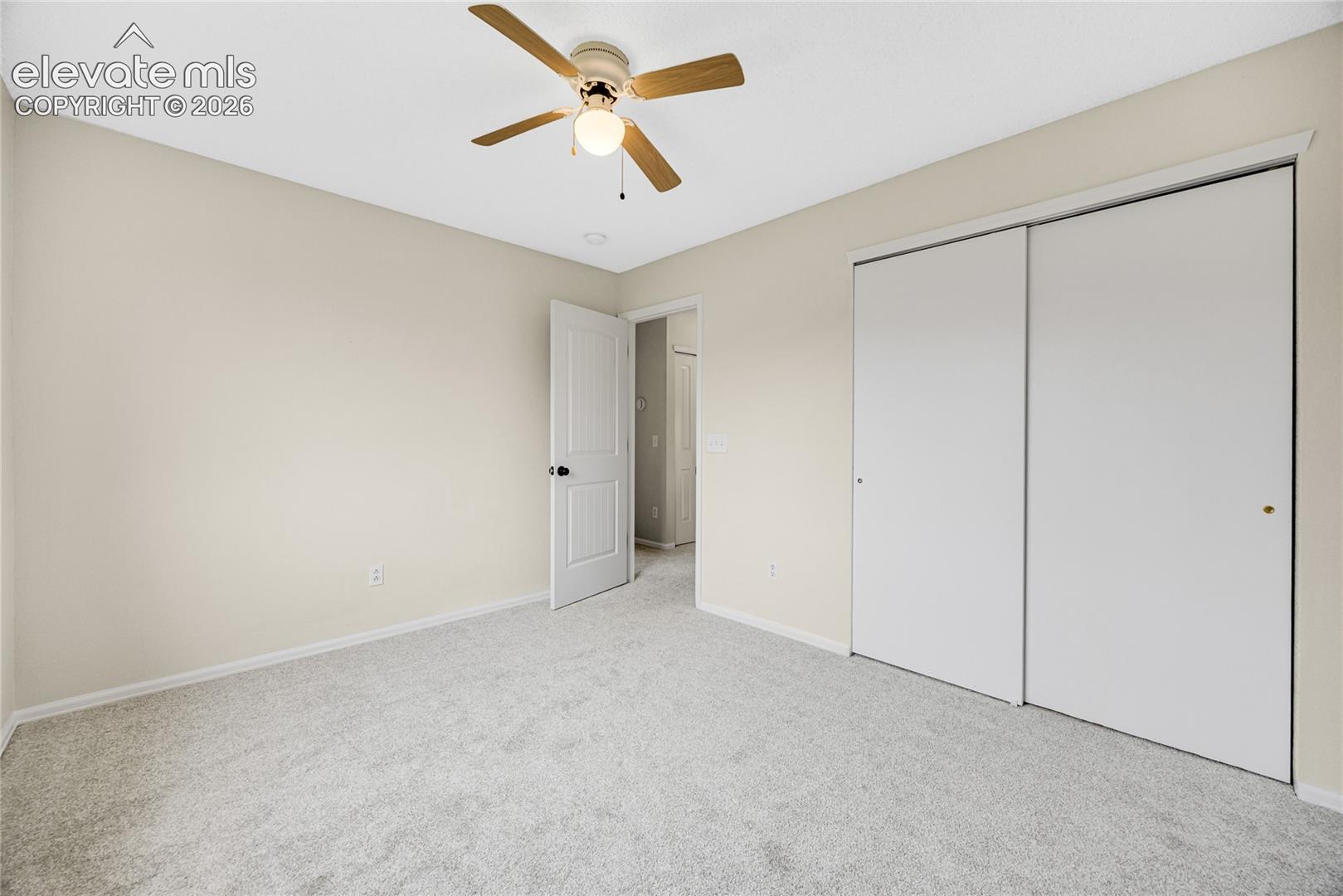 Neutral interior featuring wall-to-wall carpeting, a ceiling fan with integrated lighting, and a closet with dual sliding doors
