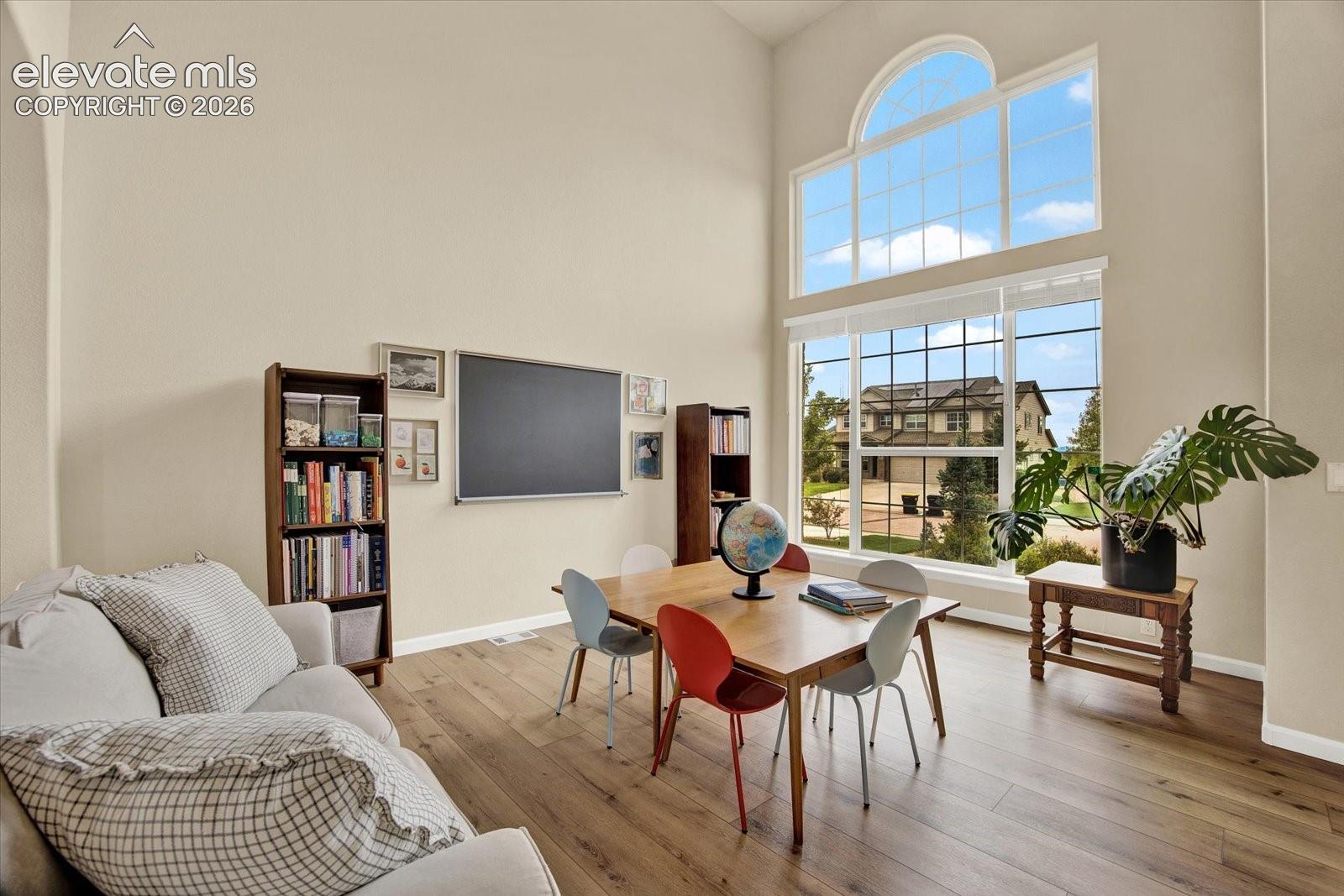 Expansive room featuring soaring ceilings, wood-finish flooring, and a floor-to-ceiling multi-pane window with an arched transom