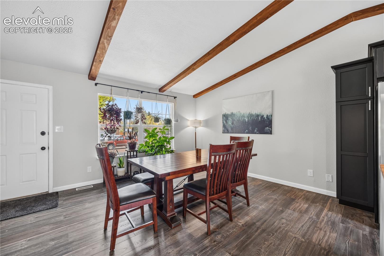 Vaulted ceiling featuring exposed wood beams, wood-finish flooring, and black built-in cabinetry