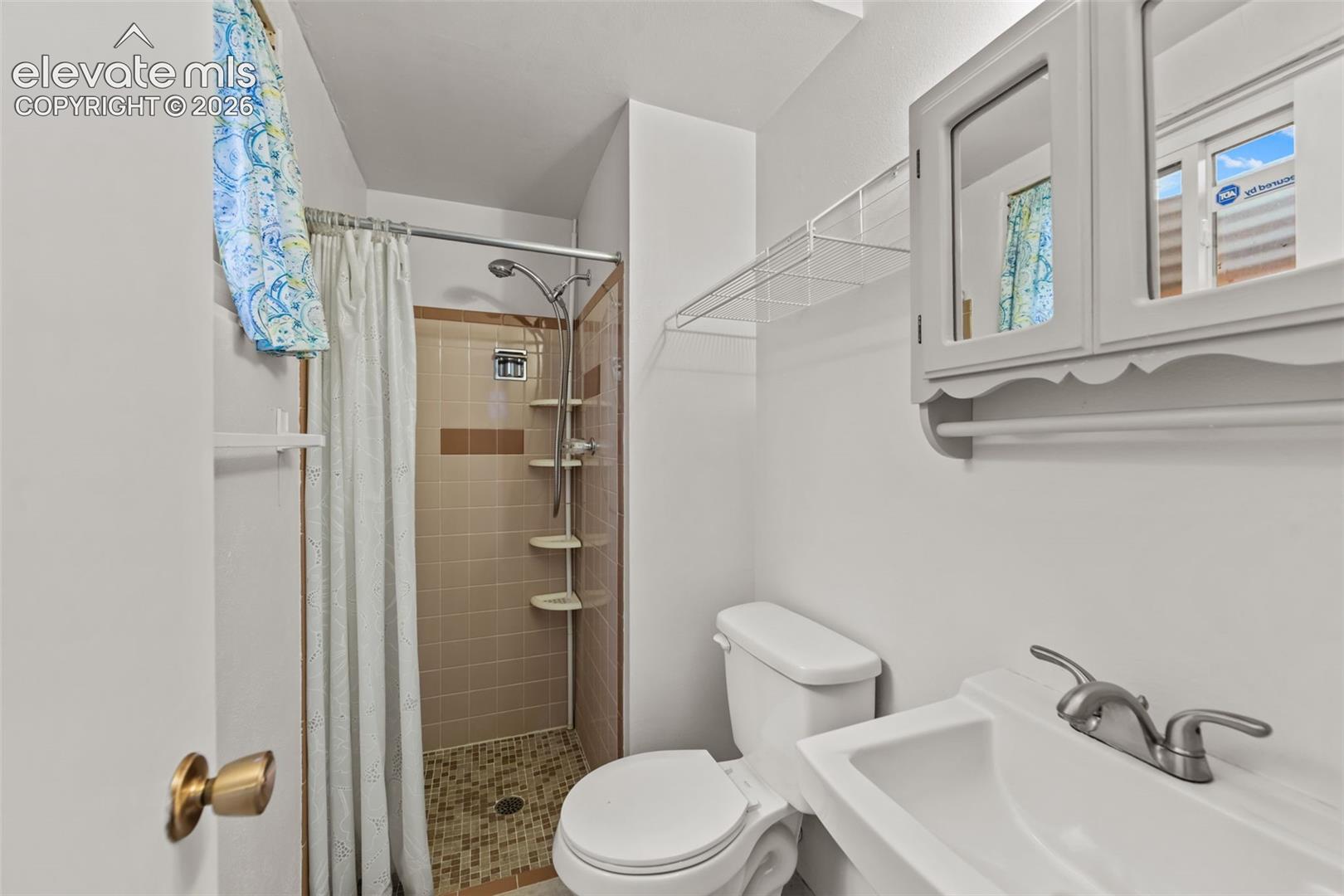 Shower with tiled walls and floor, vanity with integrated sink, and wall-mounted medicine cabinet
