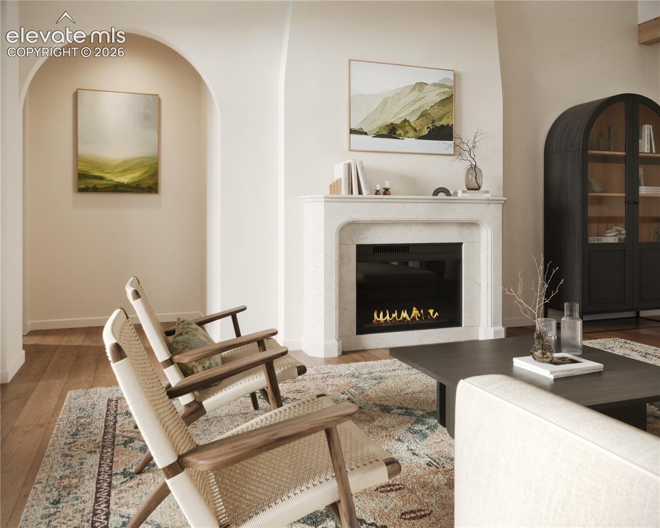Arched doorway, built-in fireplace with stone-finish mantel, hardwood flooring, and built-in arched cabinet with glass doors