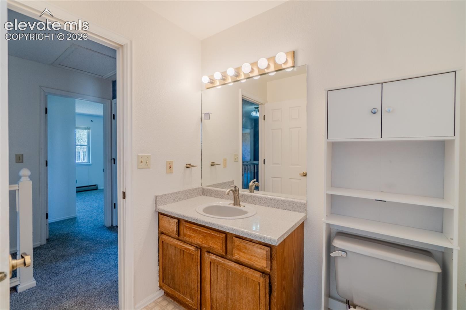 Hall bathroom with Vanity with wood-finish cabinetry, integrated sink, and a light-colored countertop