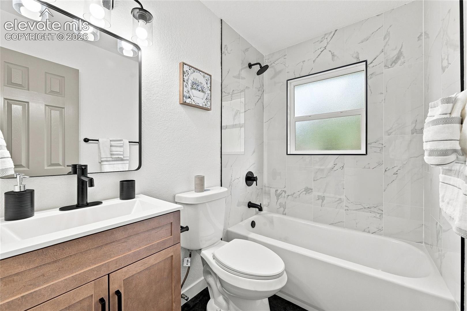 Vanity with wood-finish cabinetry, integrated sink, and matte black faucet
