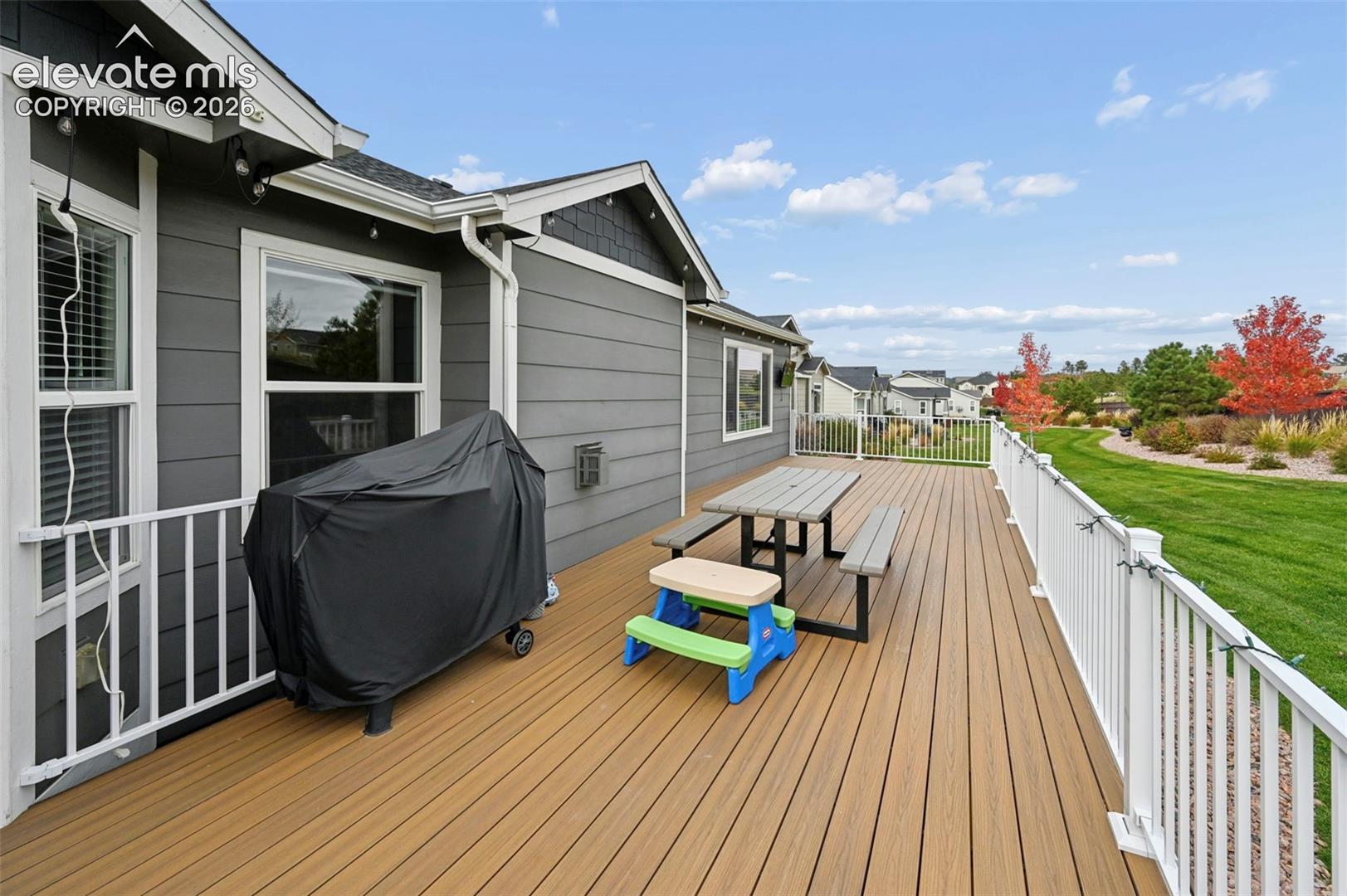 Spacious wood-finish deck featuring white metal railings and horizontal lap siding