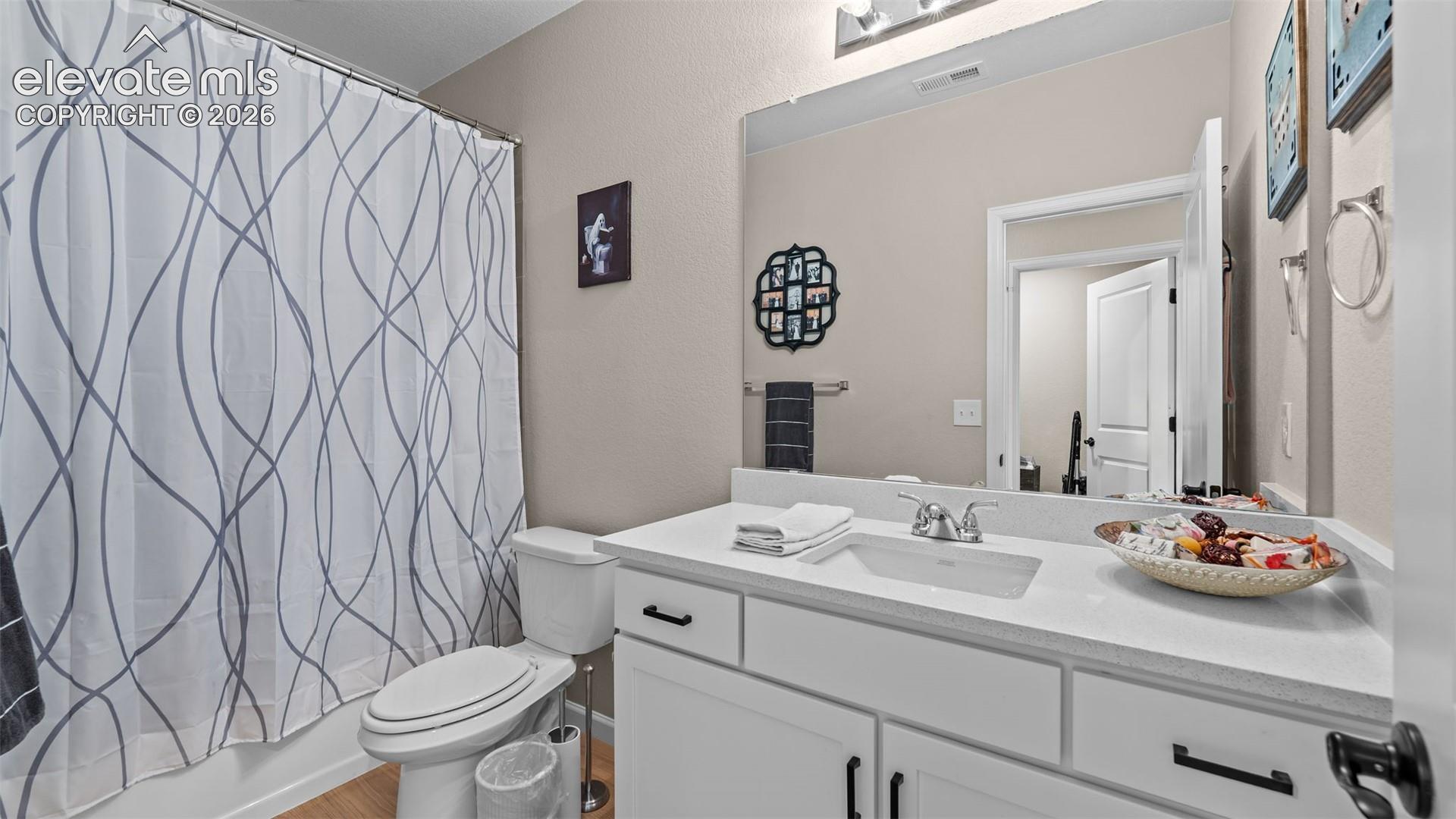 White vanity with black hardware, white rectangular sink, light-toned countertop, and an integrated mirror