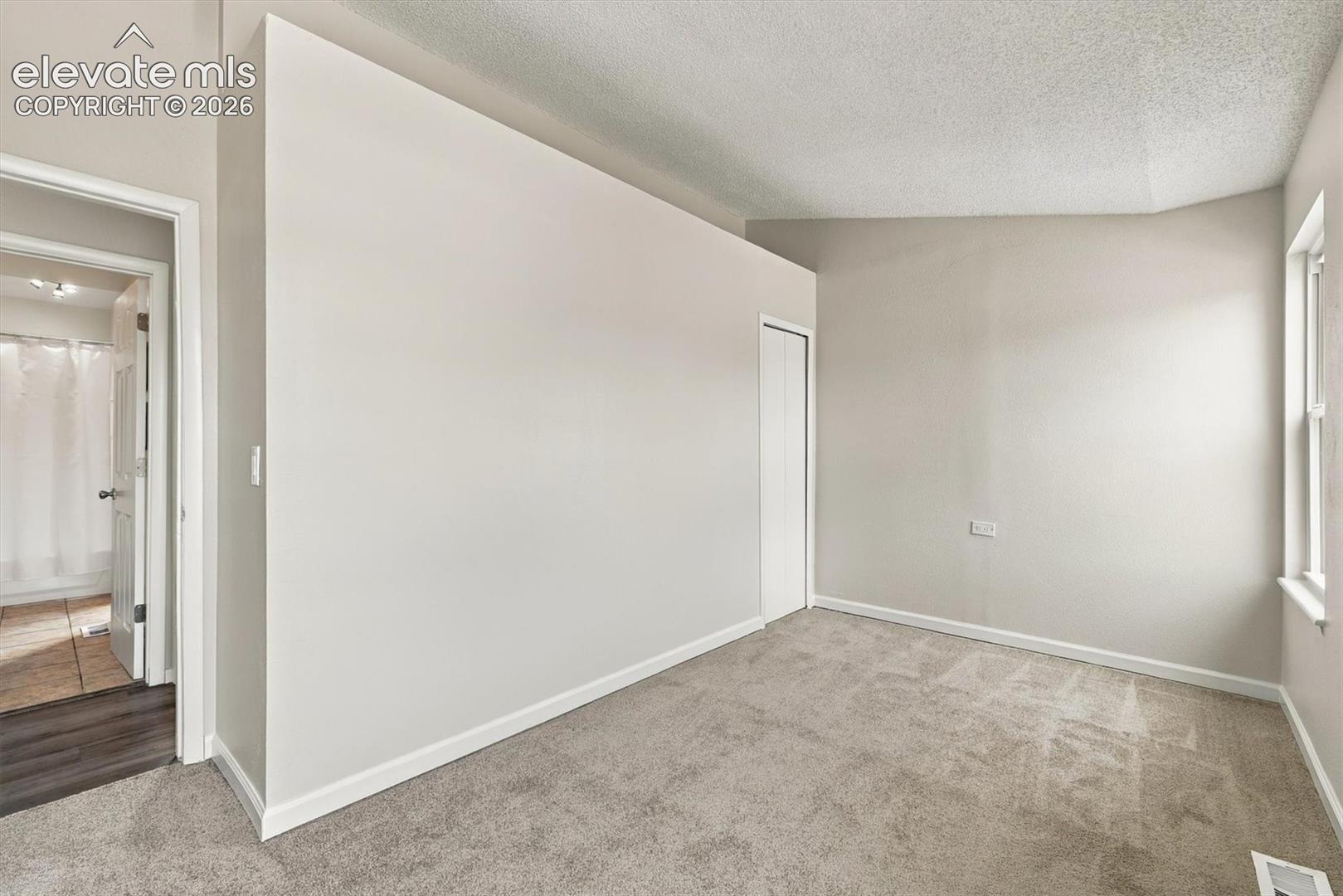 Vaulted ceilings, neutral wall tones, wall-to-wall carpeting, and a built-in closet