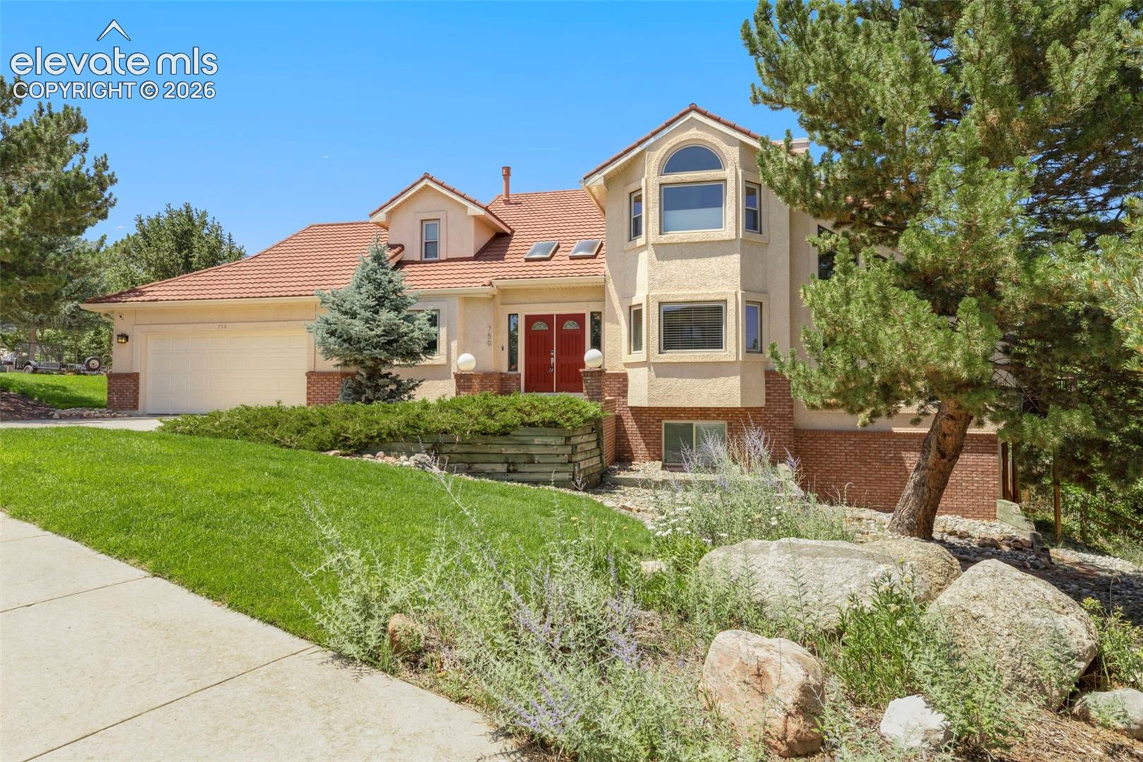 Stucco and brick exterior with a terracotta-style tile roof