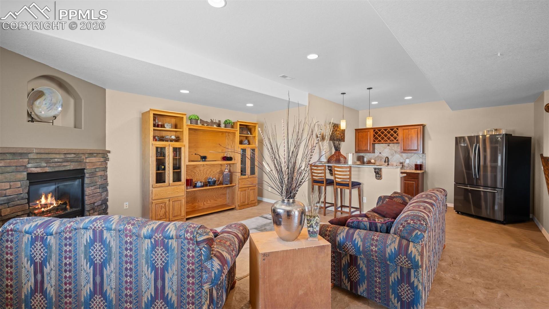 Living area featuring a fireplace, polished, stamped concrete flooring, wet bar and recessed lighting