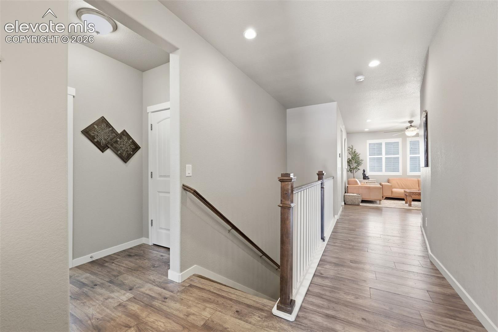 Light brown luxury vinyl plank flooring, white interior doors, and a wood banister with white spindles.